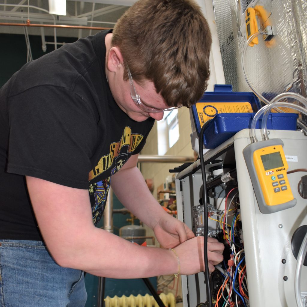  A person is meticulously working on the internal wiring of a machine