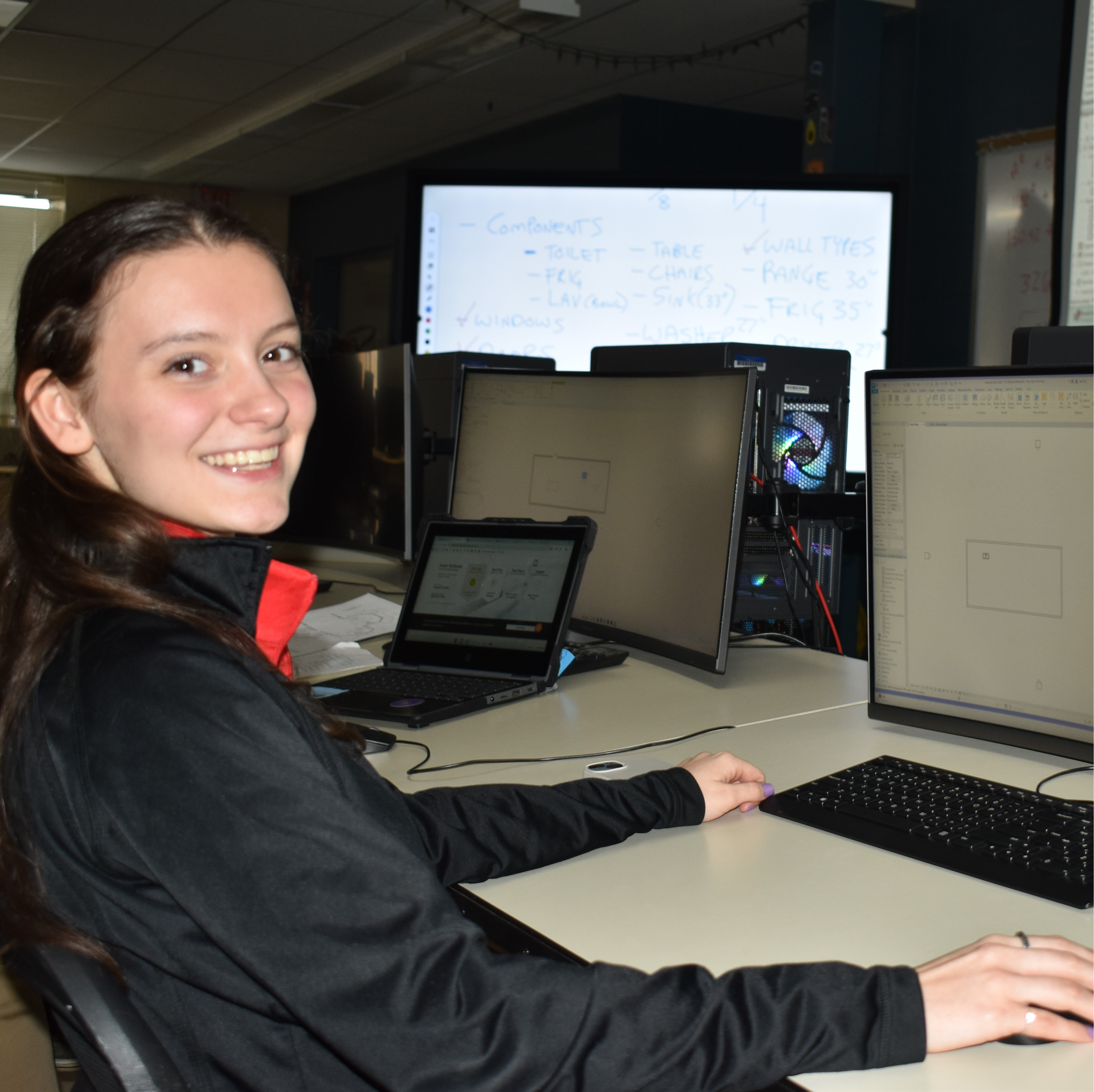 A focused individual working on a computer in a multi-station workspace