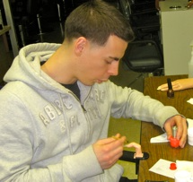 A man carefully assembling a toy with focused concentration.