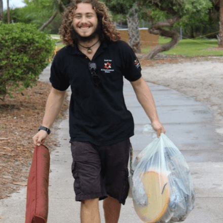 A man carrying a bag of luggage and a bag of food, ready for his journey.