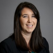 A professional woman wearing a business suit with a pleasant expression on her face.