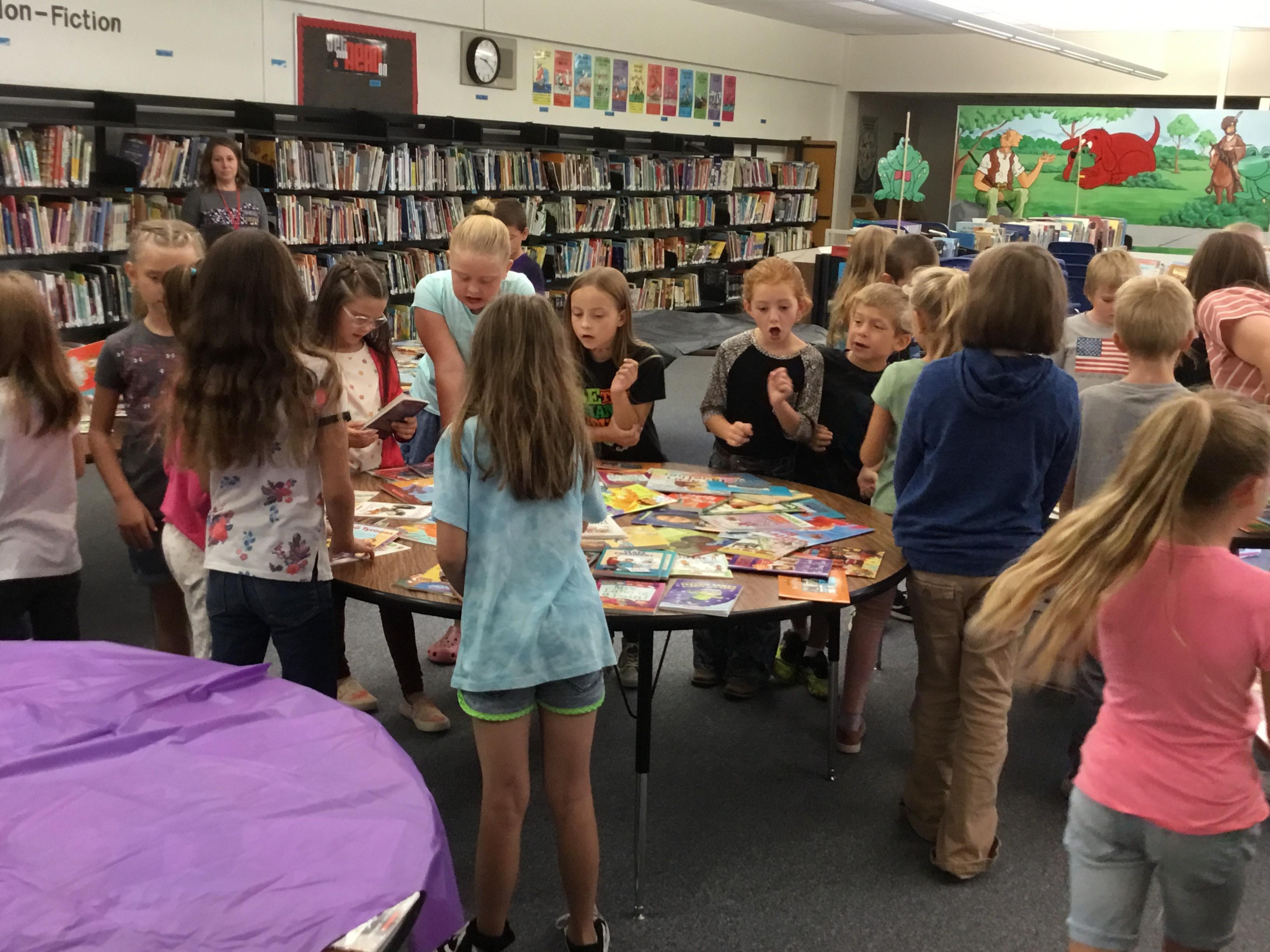 Kids gathered around a table full of books