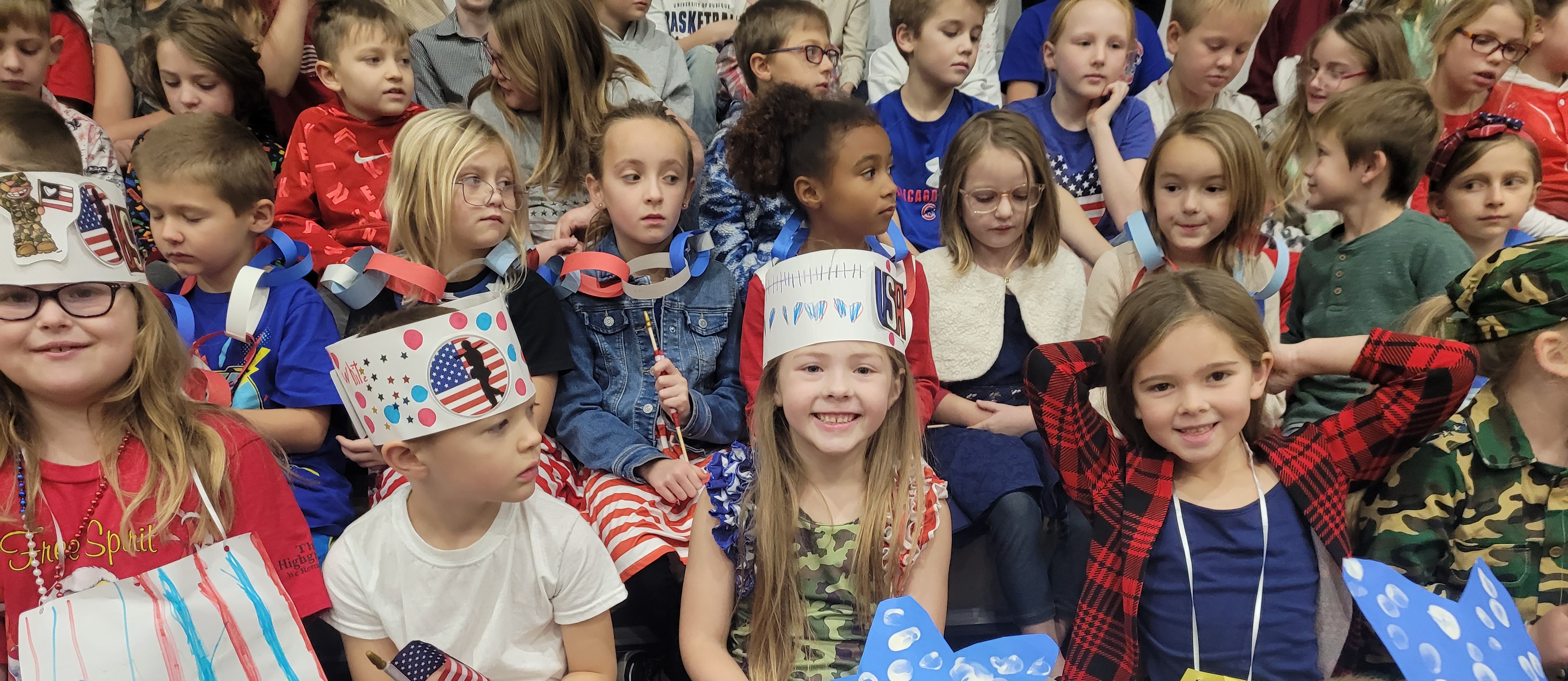children sitting together, wearing red white and blue hats made for veterans day
