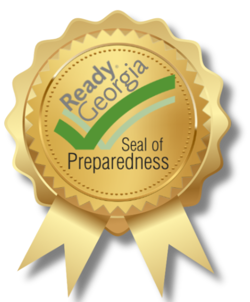 A gold seal ribbon award featuring the text 'Ready Georgia' at the top, with a green checkmark and curved lines underneath. Below, the words 'Seal of Preparedness' are displayed in a formal font. The ribbon has two tails at the bottom, giving it a distinguished certification or achievement appearance.