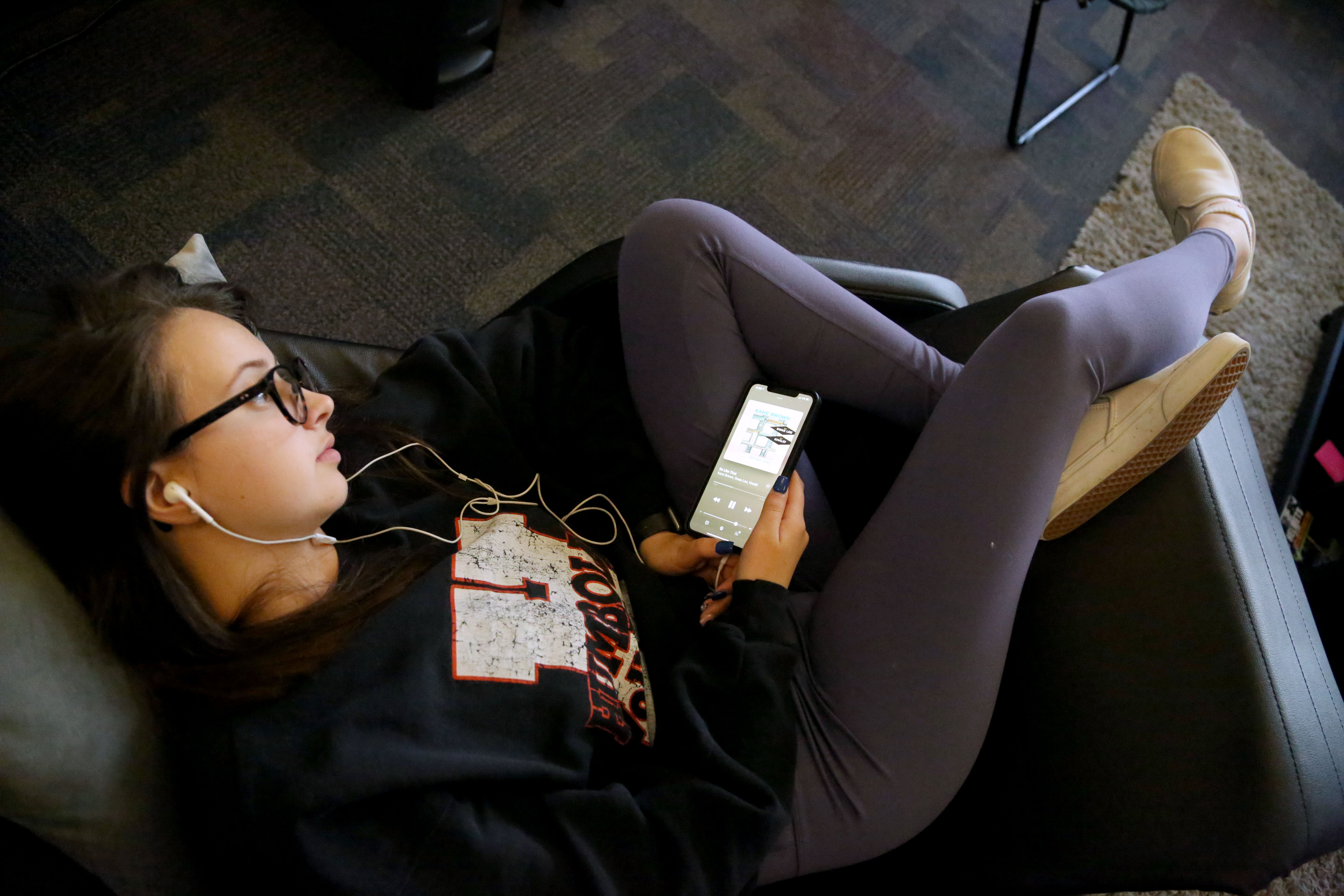 student laying down in a chair listening to music after a class