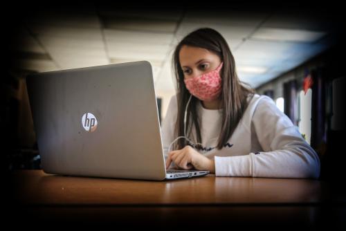 student working on her computer with a face mask