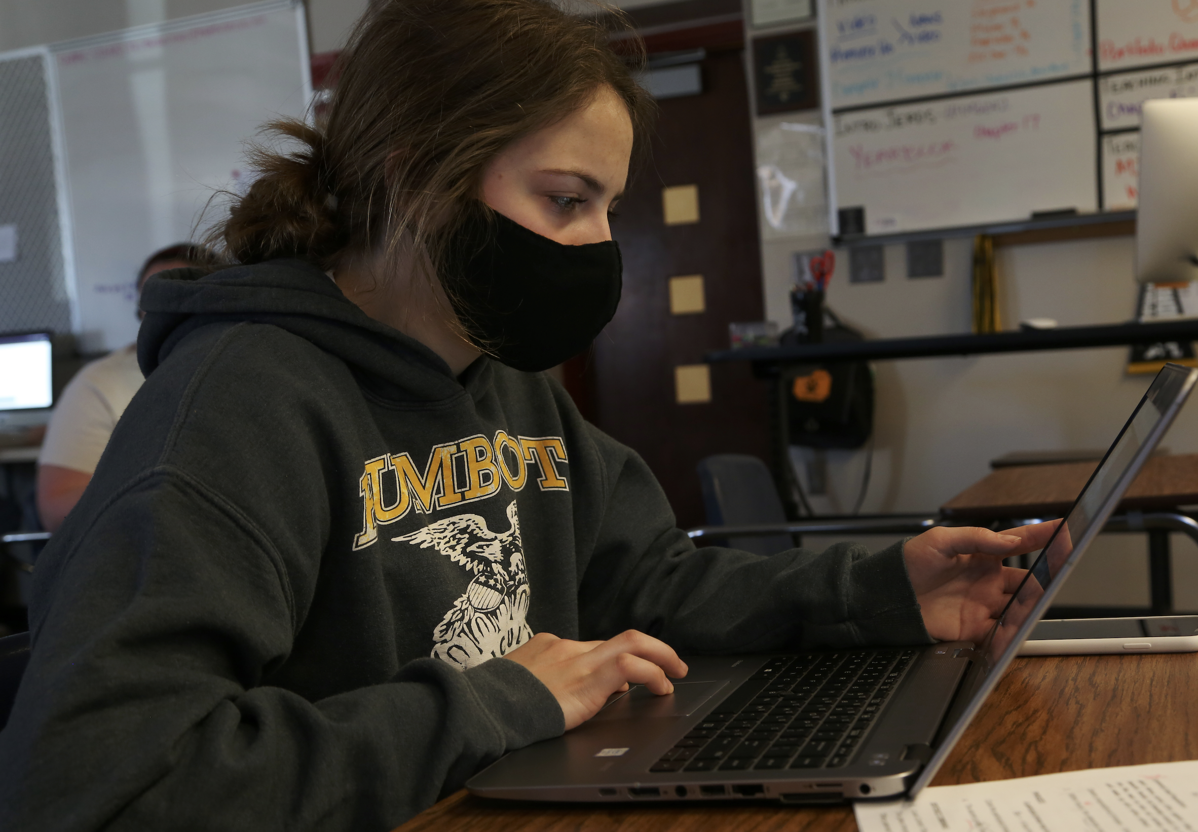 student with face mask at the school working on her computer