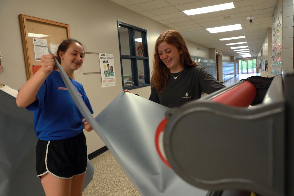 students getting paper to create a poster