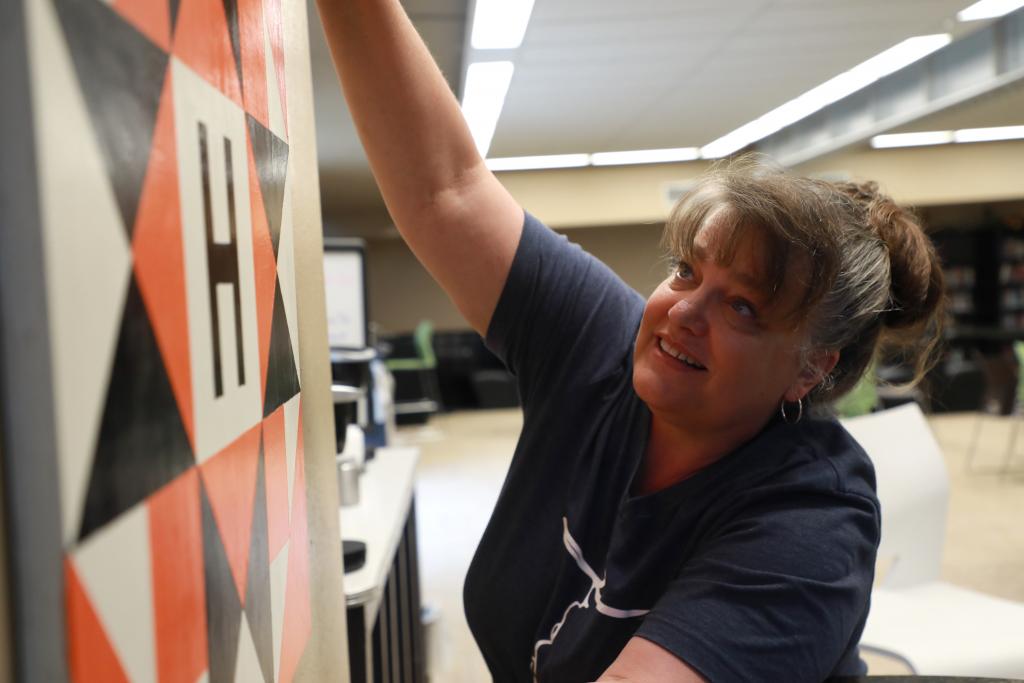 librarian hanging her painting on the wall