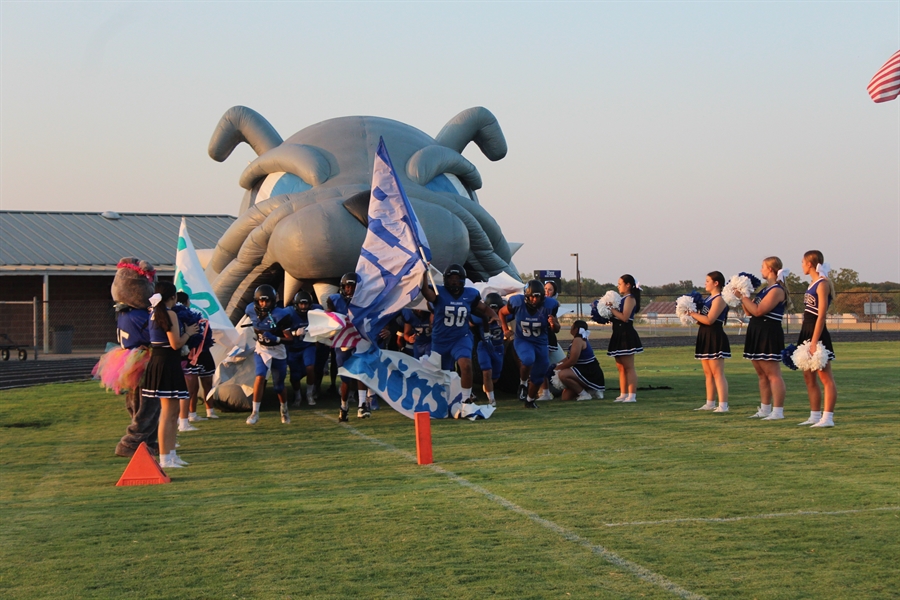 A photo of Rice District School's Cheerleading squad in front of the bulldog statue