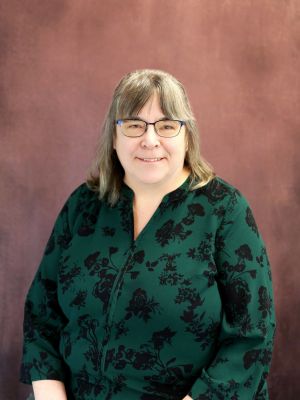 Image of a woman in glasses and a green shirt.