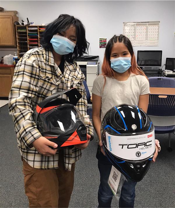 two women holding helmets in a room