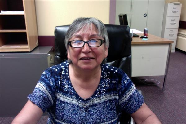 A professional woman with glasses sitting at a desk in an office.