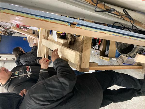 Two men measuring wooden planks