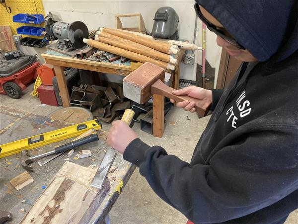 Man hammering a wooden plank