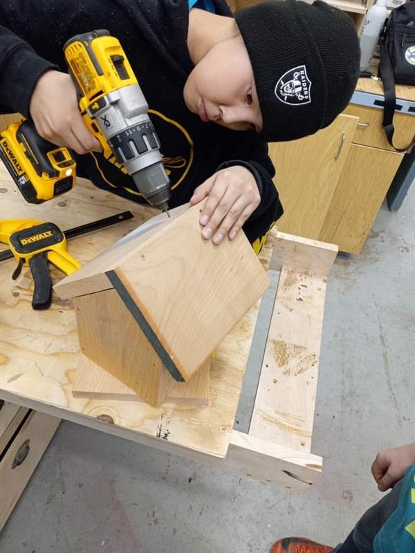 Student using powertool to drll wood