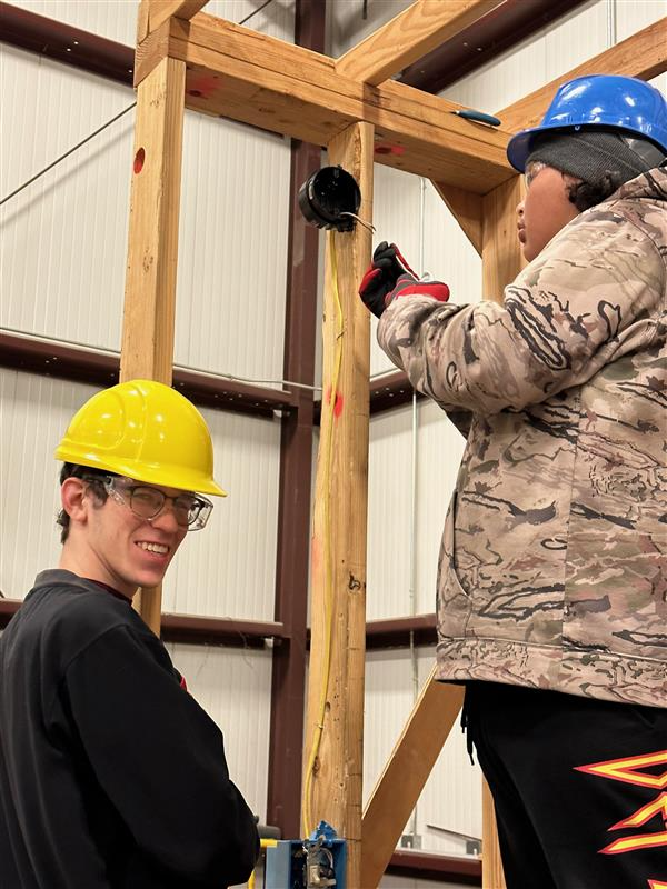 Student connecting electrical outlet while another smiles