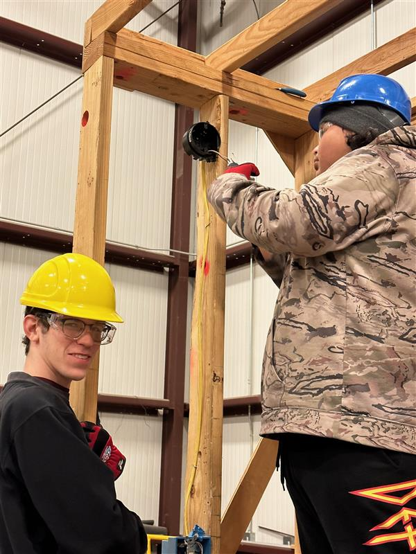 Student connecting electrical outlet while another smiles