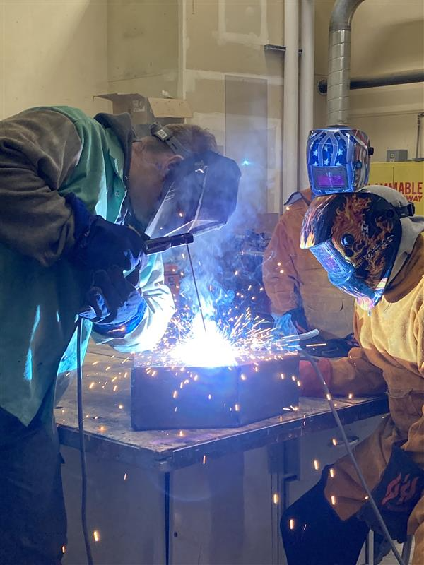 Two students welding iron