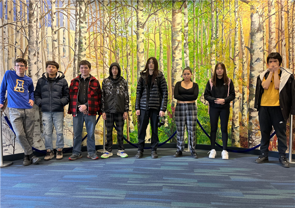 students standing posing in front of a mural