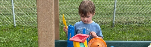 Learner playing with toys in the sandbox.