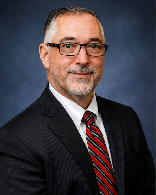 A man with glasses wearing a pin stripped suit and red tie