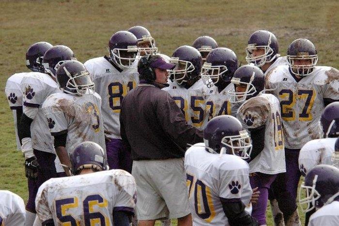 football coach in the middle of football players coaching on the field