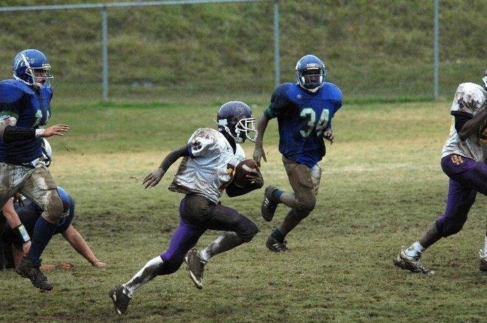 student running on the football field with their football