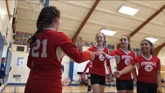 Volleyball match at an indoor gym with athletes in Red uniforms