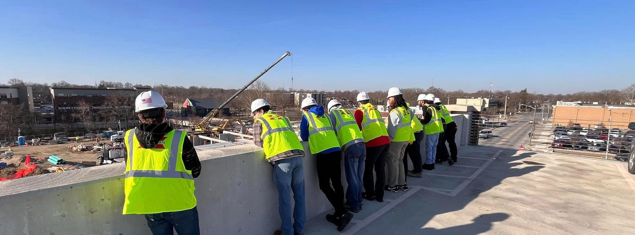 Students in hard hats on roof with construction crew
