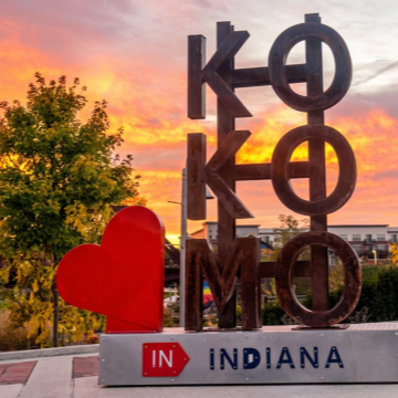 Metal sculpture with "Kokomo" stacked on "indiana" with red heart attached and sunrise in background