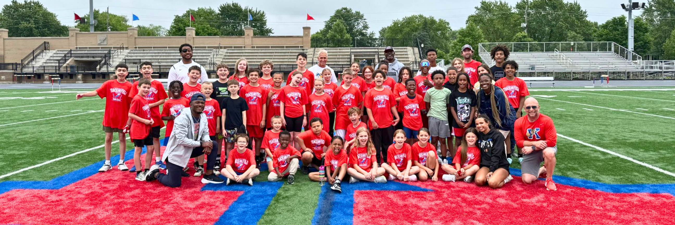 Young students in red shirts on footballl field for summer camp