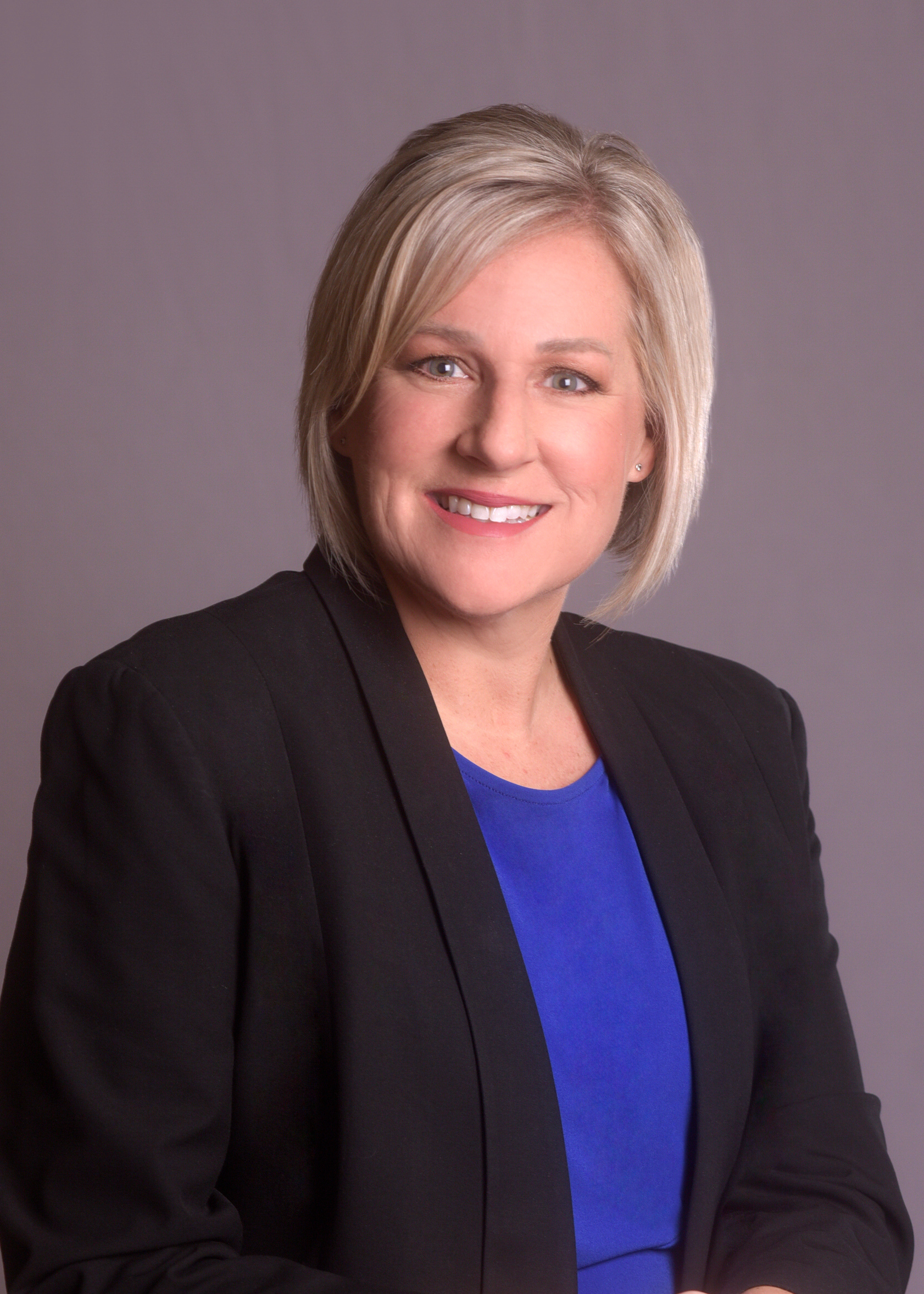 woman with blonde hair in black blazer smiling happy
