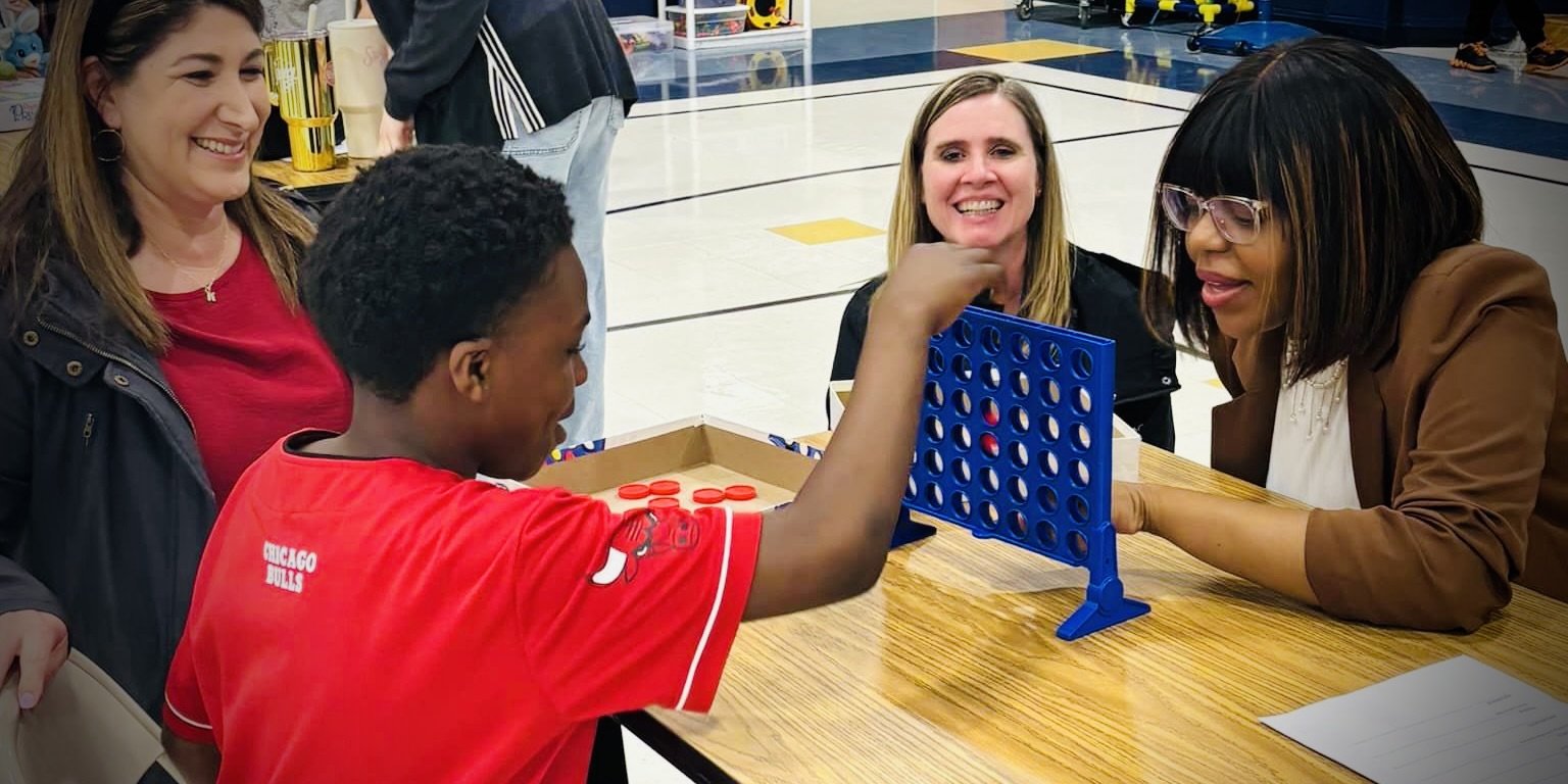 a student and his mom play Connect Four at a family event