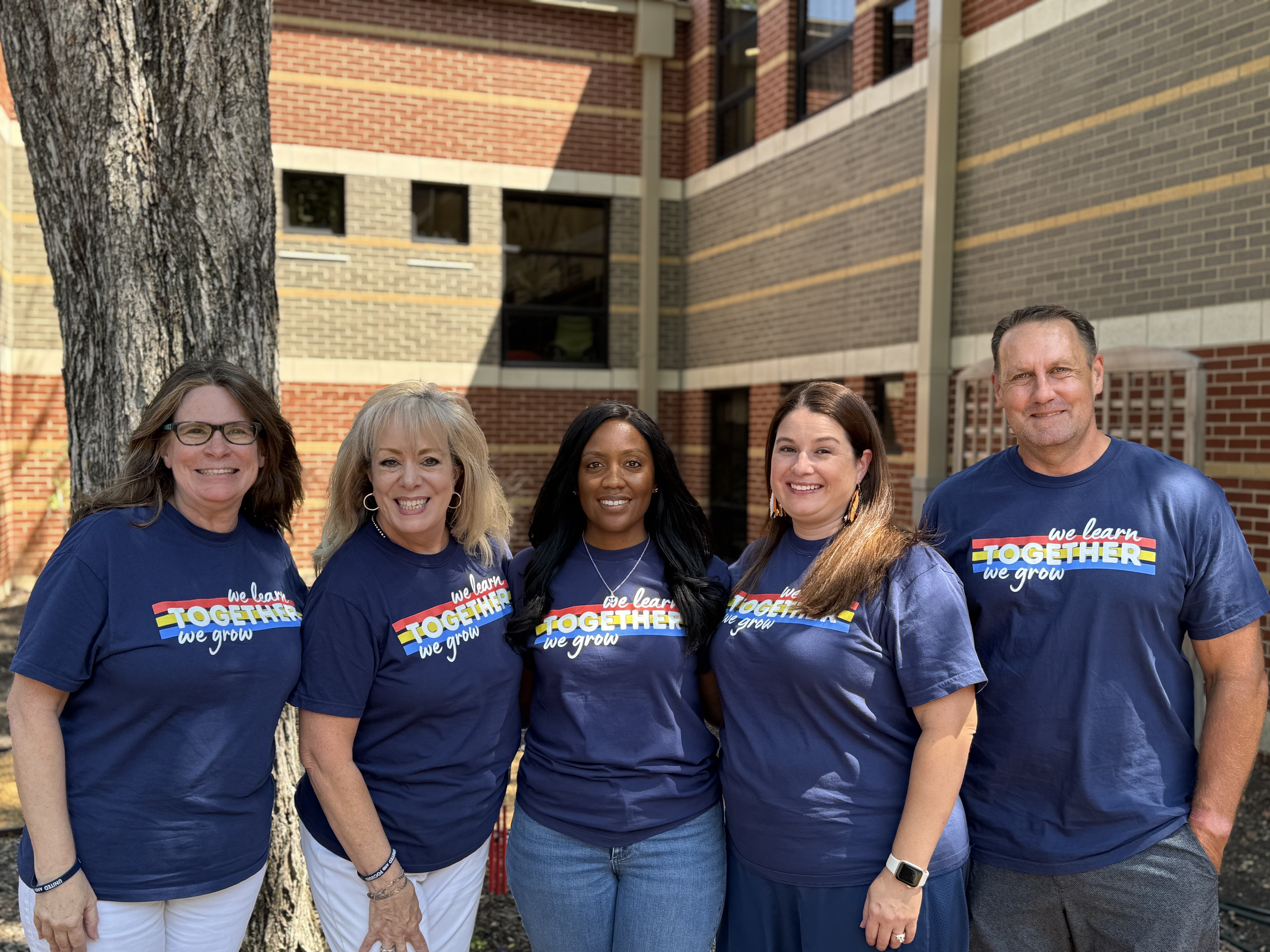 4 female and 1 male teacher standing in front of a tree