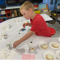 A boy sitting at a table, enjoying a plate of food.