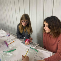 Two girls collaborating on a project at a table, engaged in focused discussion and working together.