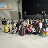 A diverse group of children sitting on the floor in a spacious room, engaged in various activities.