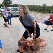 Smiling woman holding child in cute dinosaur outfit.