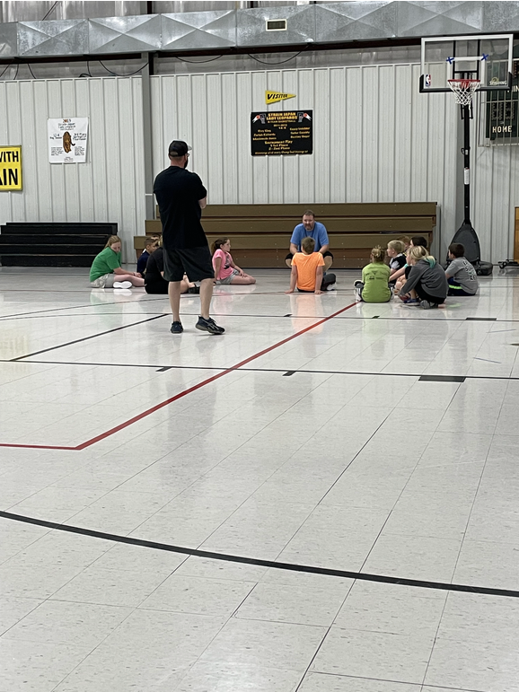 A group of people sitting on the floor in a gym