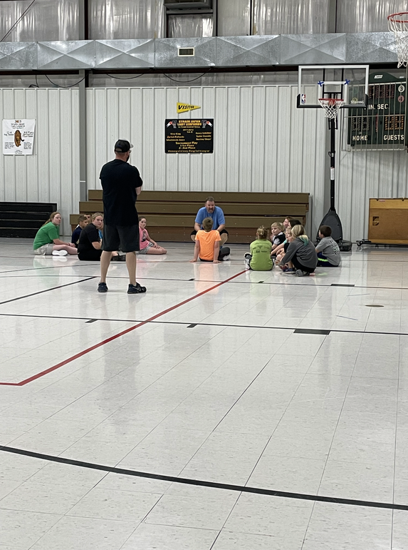 A group of people sitting on the floor in a gym