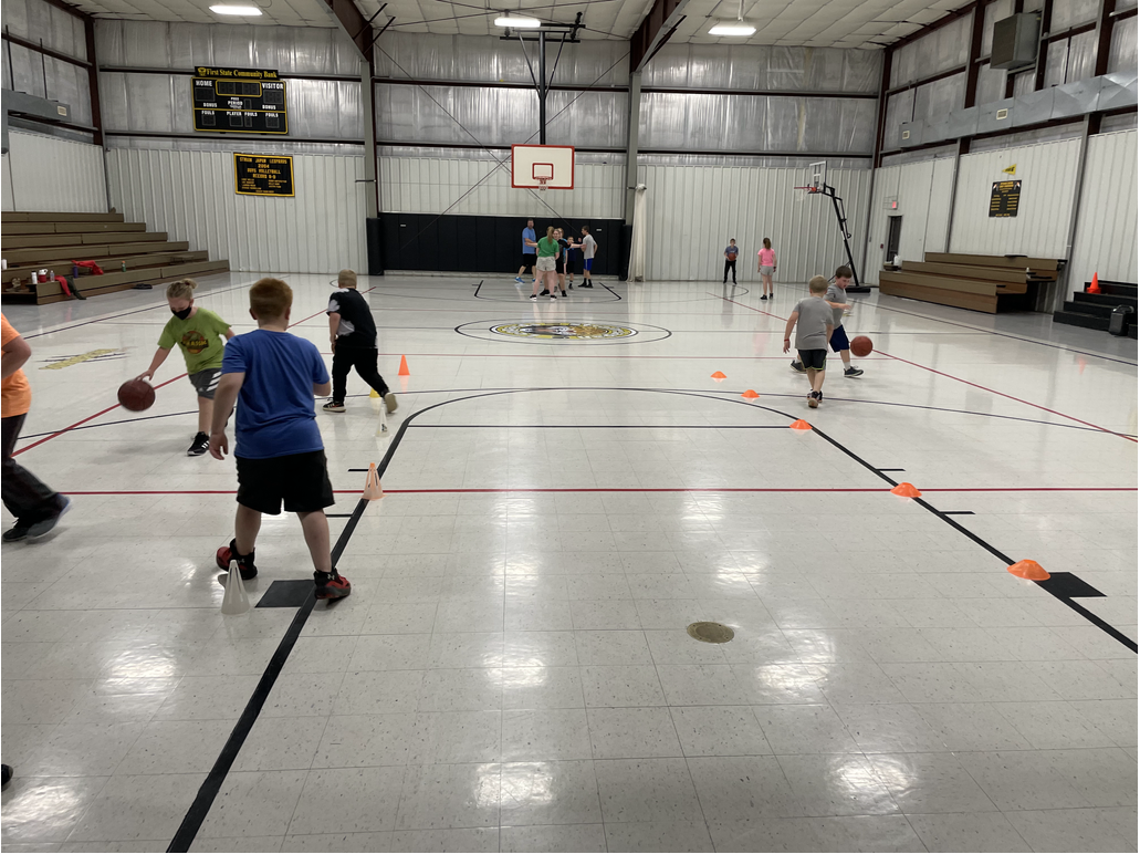 A group of kids playing basketball in a gym.