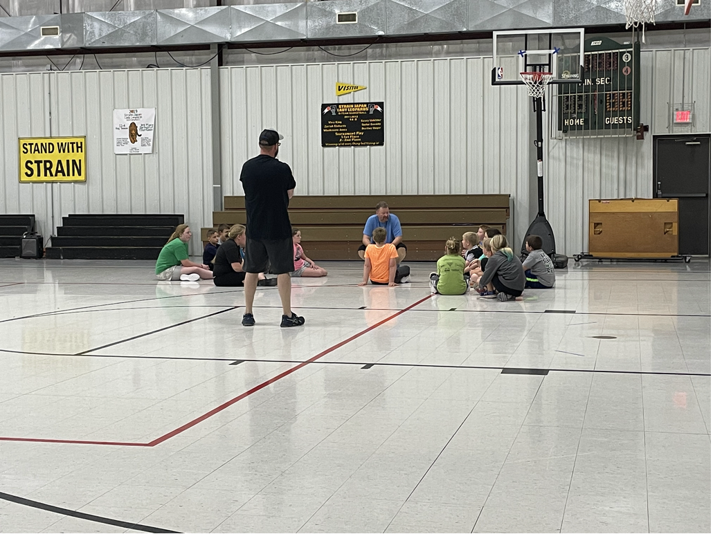 A group of people sitting on the floor in a gym