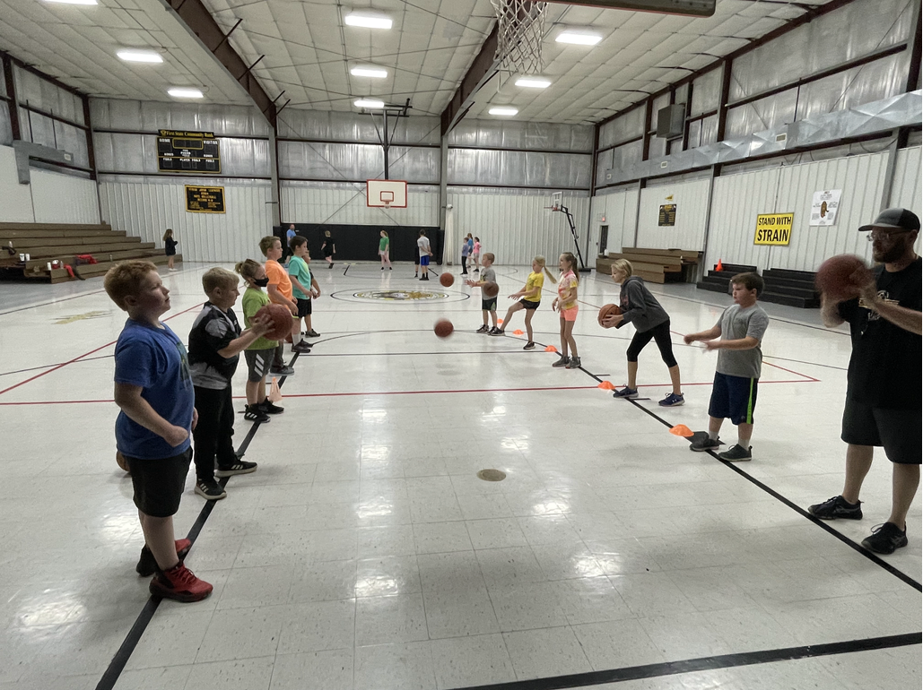 A group of kids playing basketball in a gym.