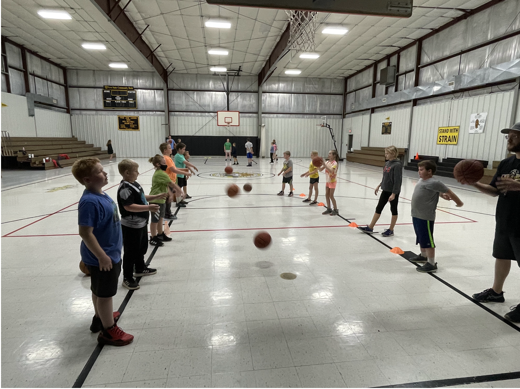 A group of kids playing basketball in a gym.