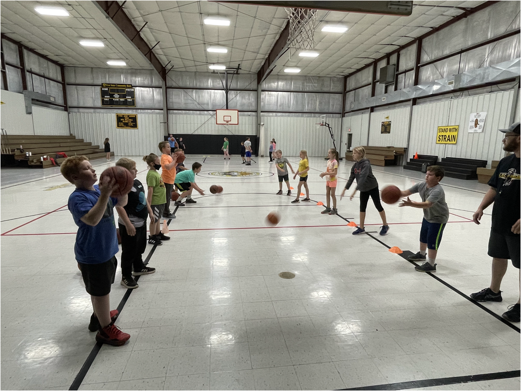 A group of kids playing basketball in a gym.