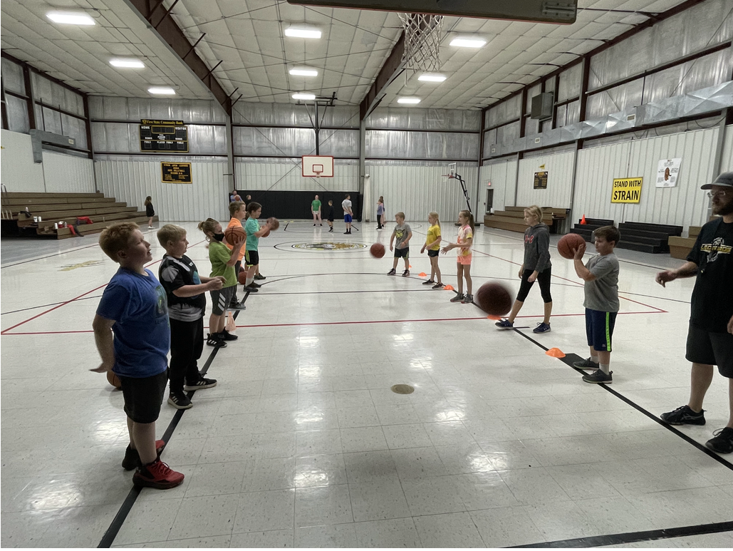 A group of kids playing basketball in a gym.