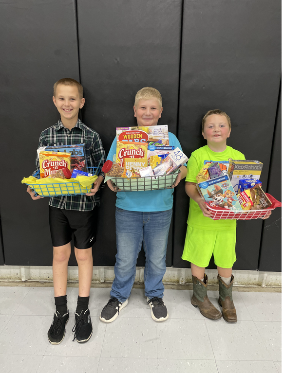 Three young boys holding baskets of food in front of a black wall