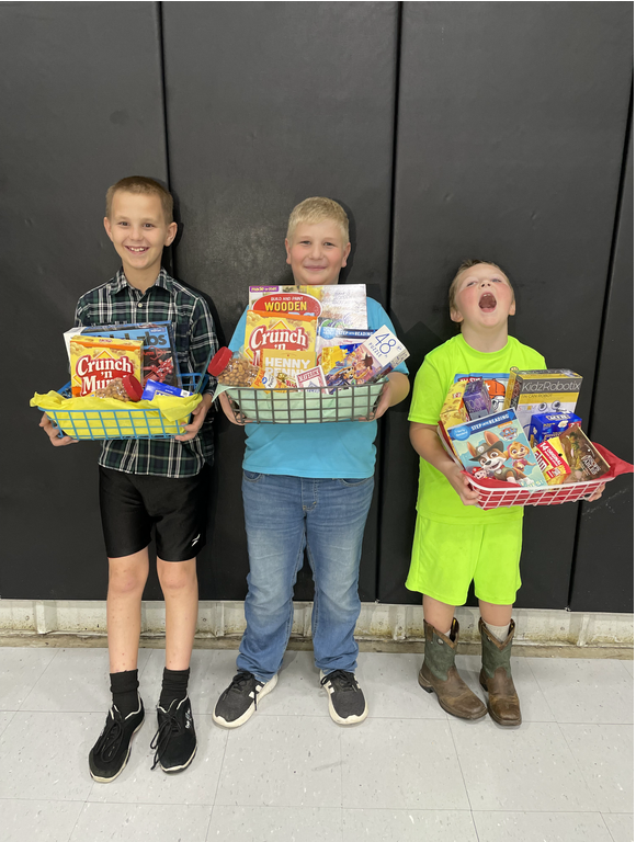 Three young boys holding baskets of food in front of a black wall