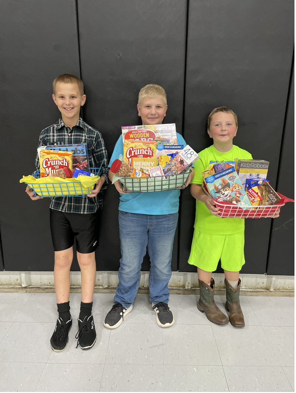 Three young boys holding baskets of food in front of a black wall